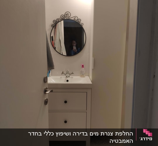 כיור אמבטיה עם ברז ומראה עגולה